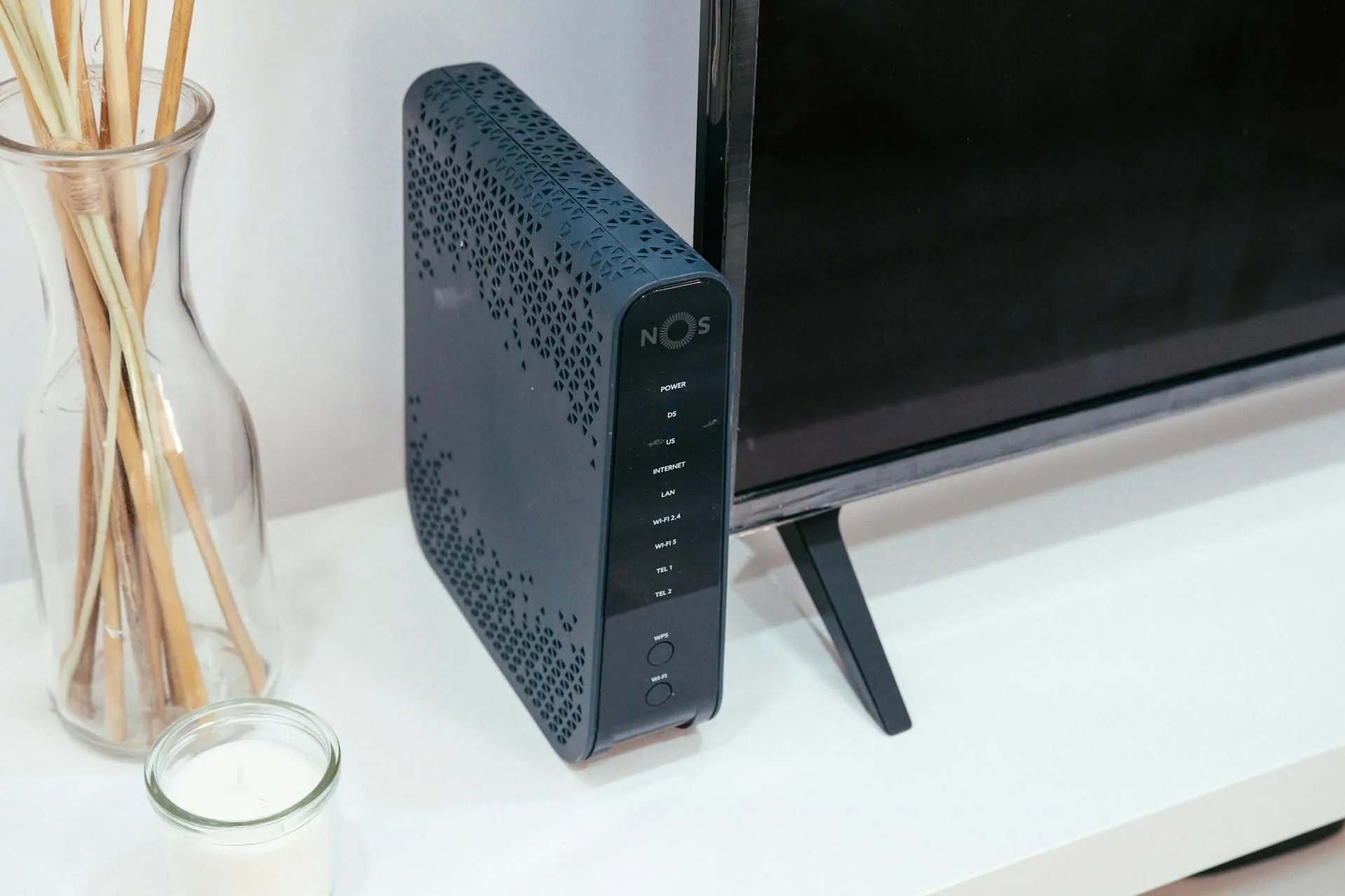 Bộ định tuyến Wi-Fi gia đình đặt cạnh TV và nến thơm, tượng trưng cho kết nối internet ổn định