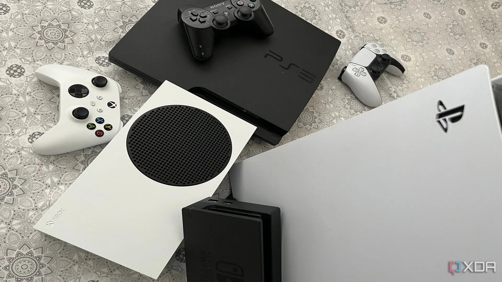 Bộ sưu tập các máy chơi game console PlayStation 5, Xbox Series X, Nintendo Switch và PlayStation 3, thể hiện khả năng tương thích ngược và thư viện game đa dạng của thế hệ console hiện tại.