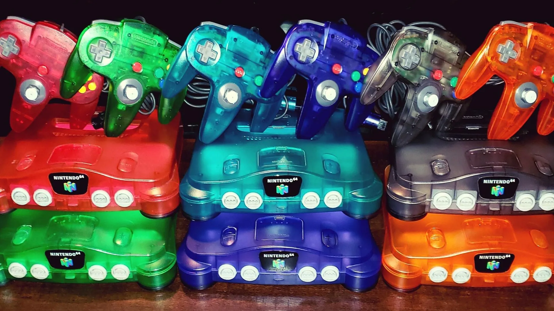Bộ sưu tập các máy chơi game Nintendo 64 với nhiều màu sắc và kiểu dáng khác nhau, bao gồm các phiên bản trong suốt và màu sắc rực rỡ, thể hiện sự đa dạng về phong cách của dòng console này.