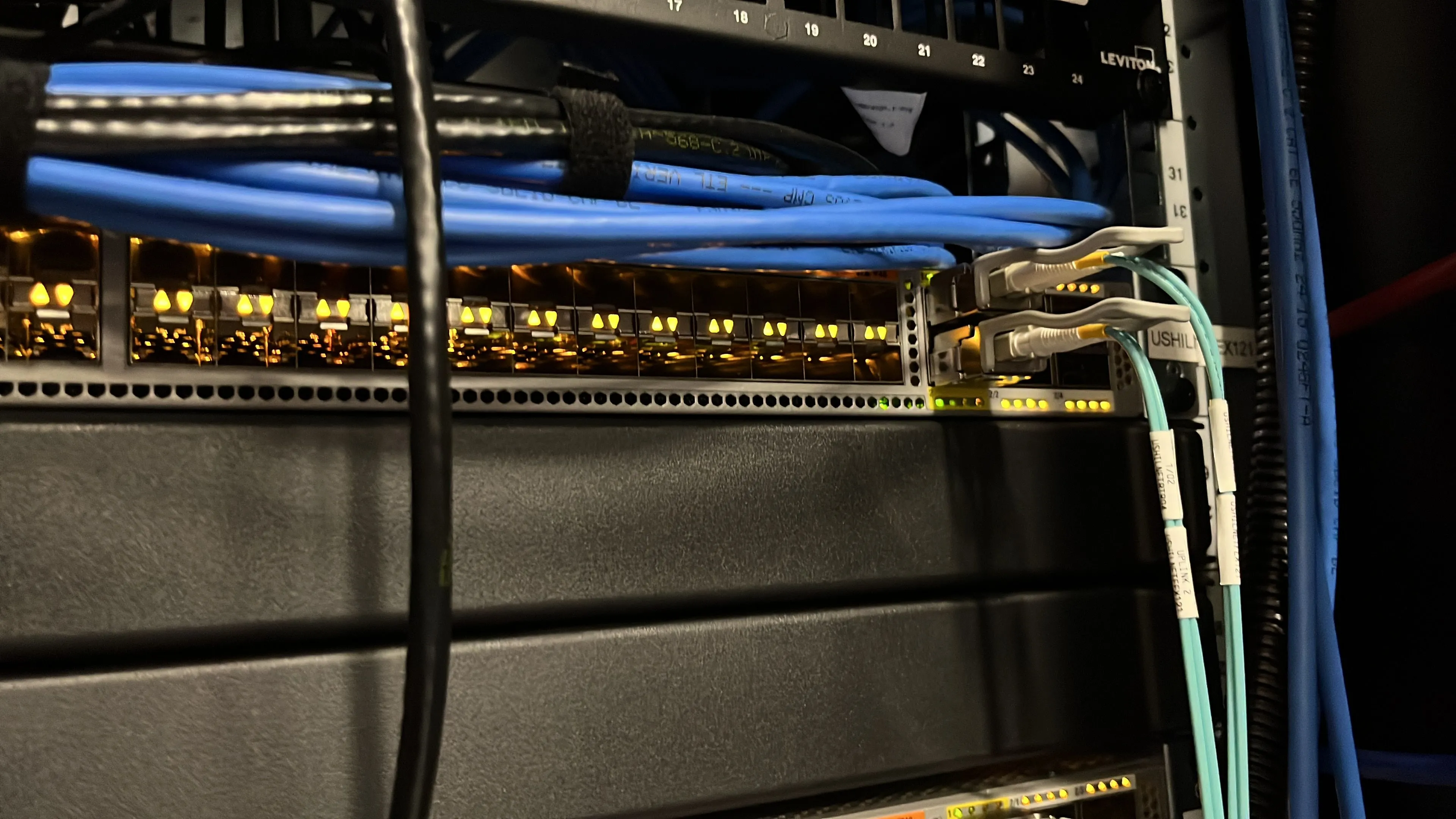 Hệ thống mạng trong phòng lab tại nhà với switch và cáp được sắp xếp gọn gàng, thể hiện việc quản lý hạ tầng mạng hiệu quả.