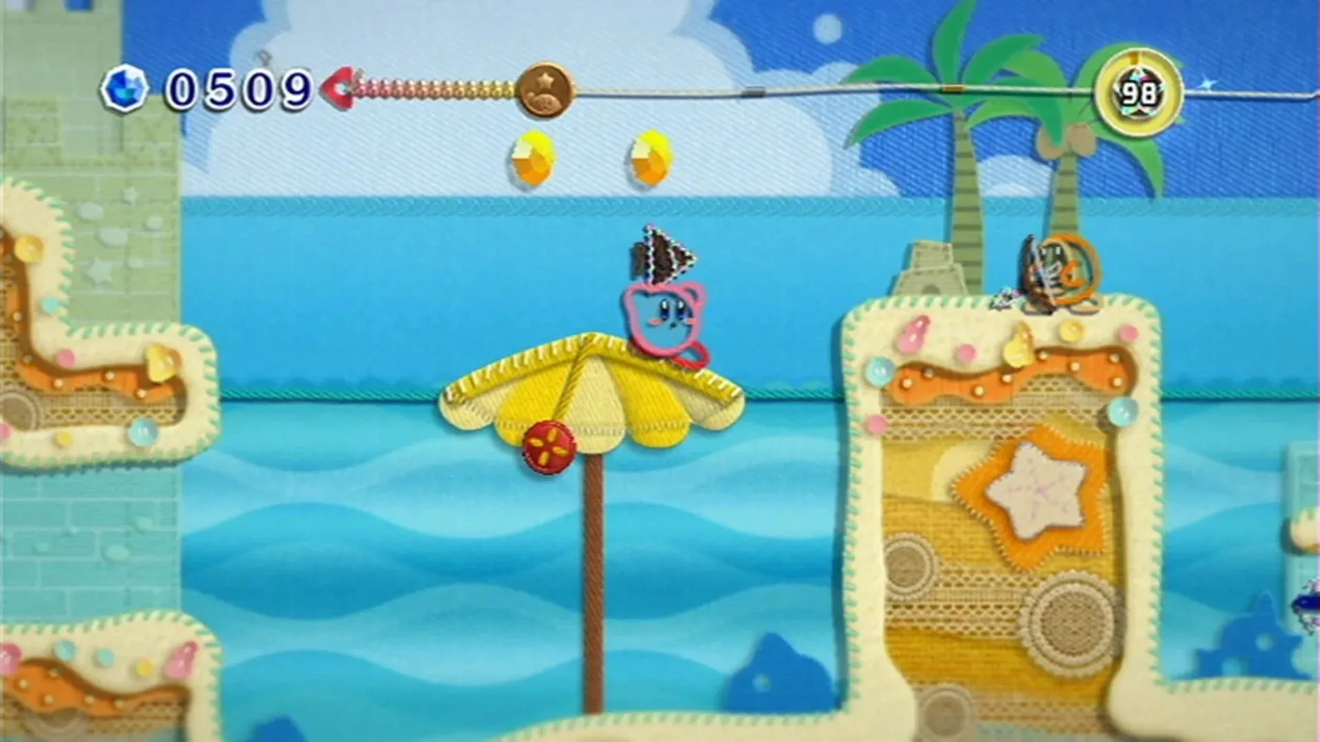 Kirby đứng trên bãi biển trong game Kirby's Epic Yarn, với phong cách đồ họa sợi len độc đáo trên Nintendo Wii