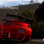 Một chiếc Mazda màu cam đang đua trên đường phố Los Angeles về đêm, phía sau là biểu tượng Hollywood, trong game Midnight Club: Los Angeles.