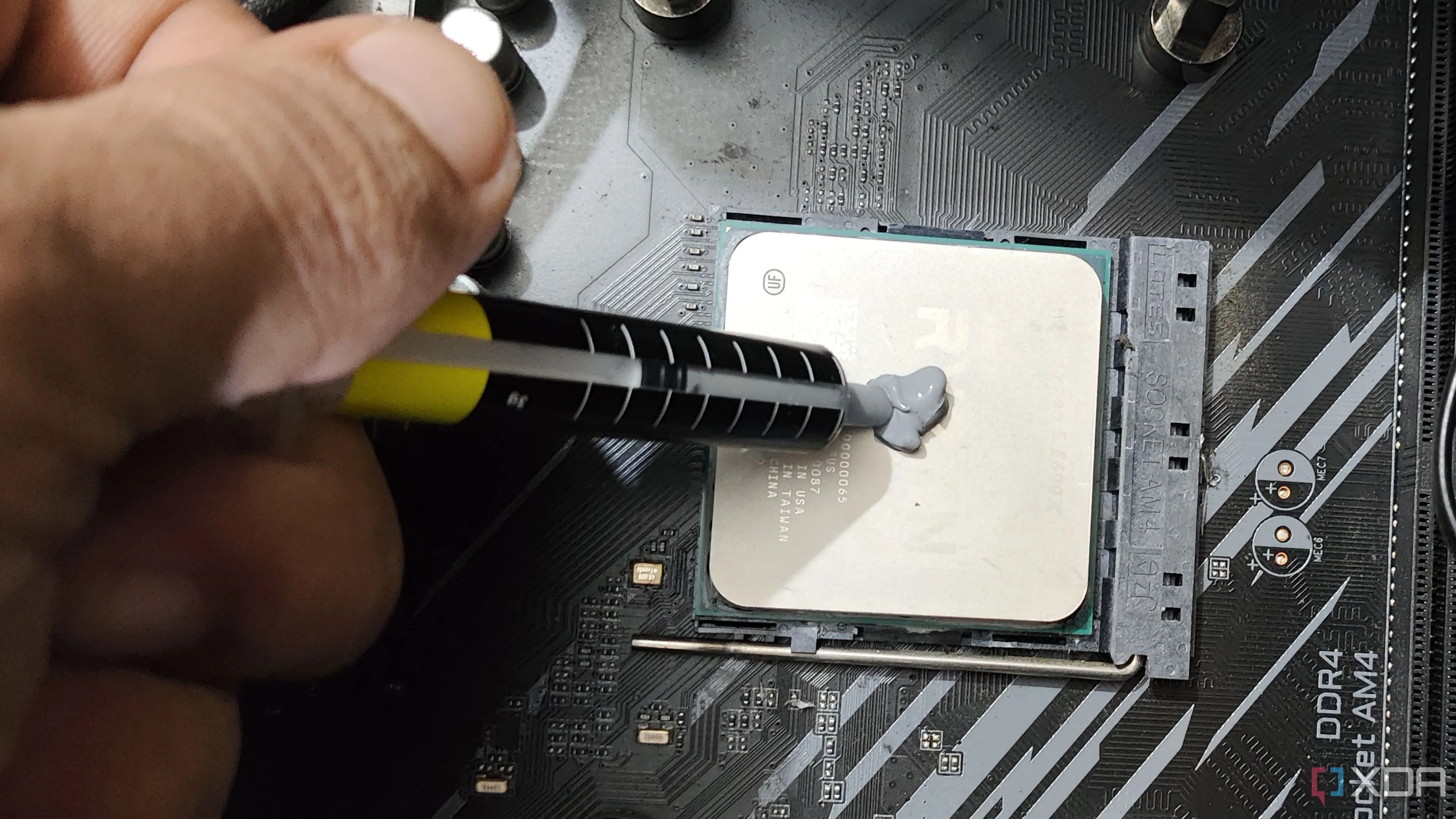 Một người đang bôi keo tản nhiệt lên Ryzen 5 5600X.