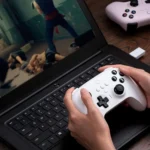 Người dùng đang chơi game trên laptop với tay cầm 8BitDo Ultimate Wireless