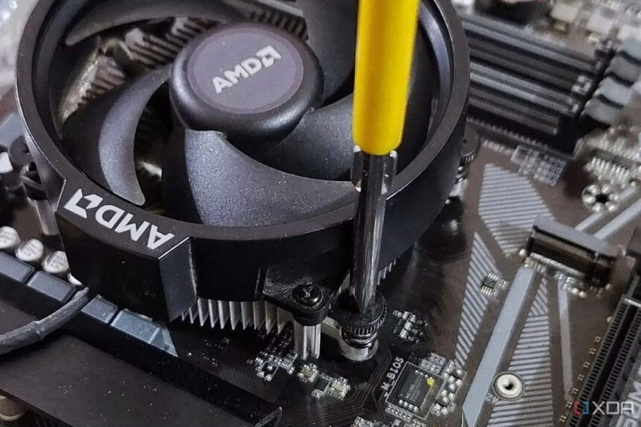 Tản nhiệt AMD stock đang được vặn vào bo mạch chủ bằng tuốc nơ vít